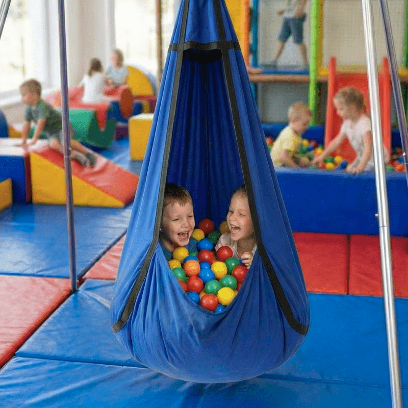 Sensory hammock swing pod for autism and ADHD, child sitting inside with play balls