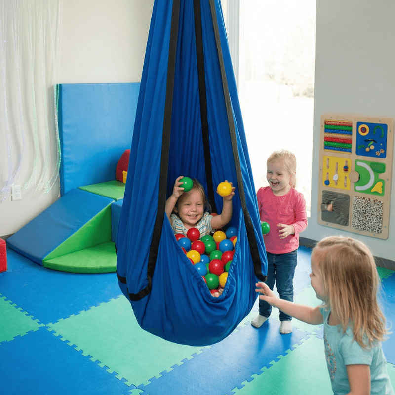 Sensory hammock swing pod for autism and ADHD, child sitting inside with play balls